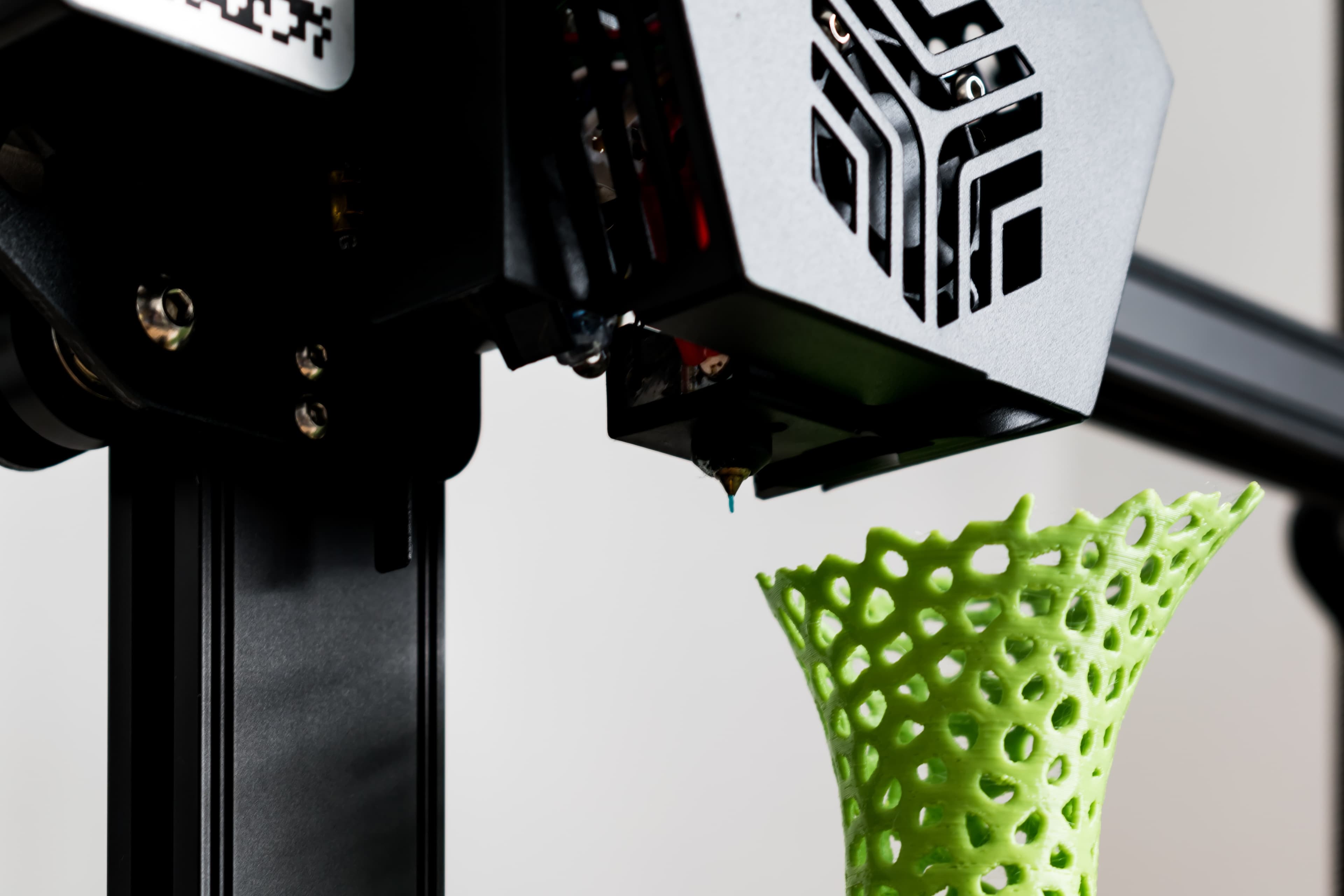 AK Innovations workshop background with 3D printing equipment and materials
